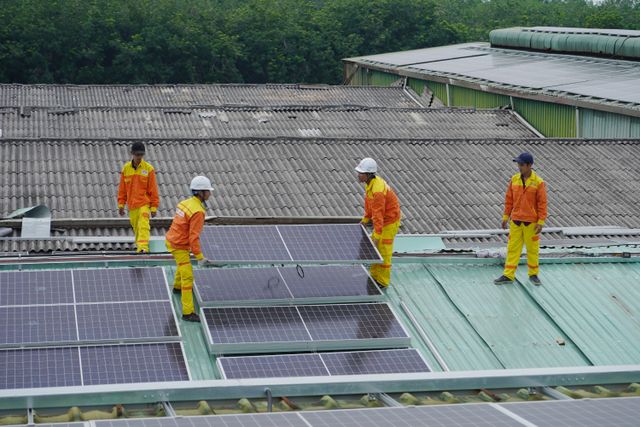 Quarry Management Workers installing solar panels on a roof for sustainable energy solutions.