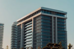 Building Up or Building Wide? A modern highrise building with glass facade against a clear sky, showcasing urban architecture.