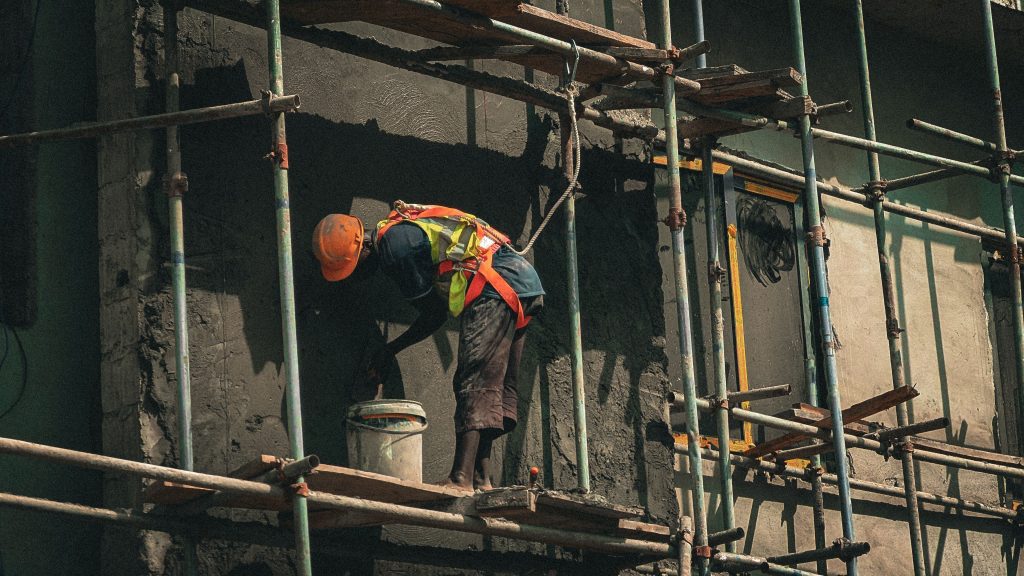 Building Up or Building Wide? A construction worker applies plaster on a building facade in Abuja, Nigeria.