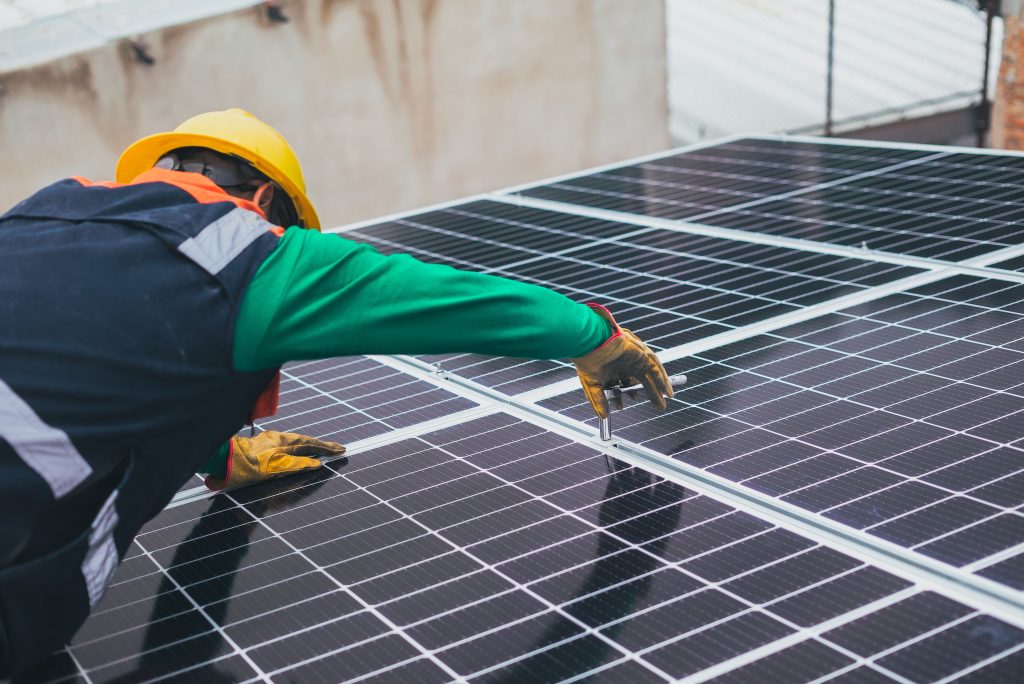Solar System Maintenance: How to Protect Performance and Battery Life Technician installing solar panels on a rooftop for sustainable energy solutions.